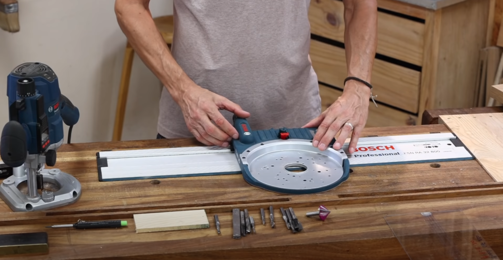 Guide de défonceuse fixé sur un rail pour un usinage perpendiculaire en plein panneau