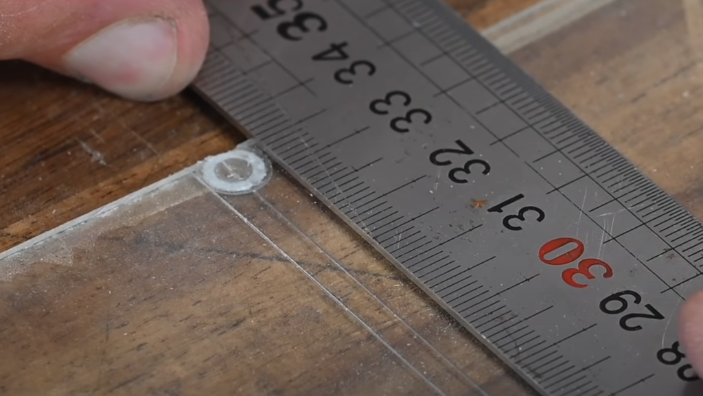 Traçage des repères de largeur de fraise à l’aide d’une règle sur un gabarit de défonceuse